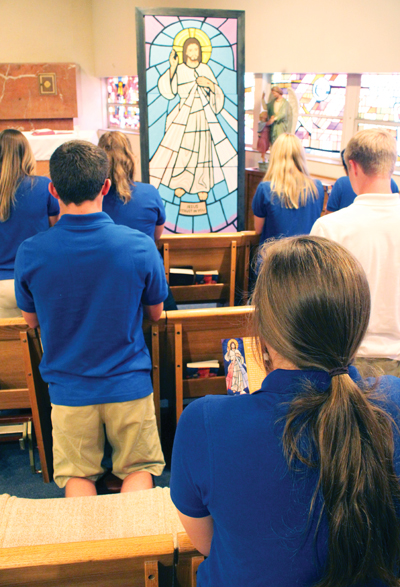 REFLECTION ON MERCY - Students from St. Cecilia High School pray before a 9-foot mural of the Divine Mercy image. Parishioners are invited to participate in the completion of the mural prior to the Sept. 11 ‘Celebration of Creation’ to reflect on the Year of Mercy. (Photo courtesy Father Adam Sughroue)